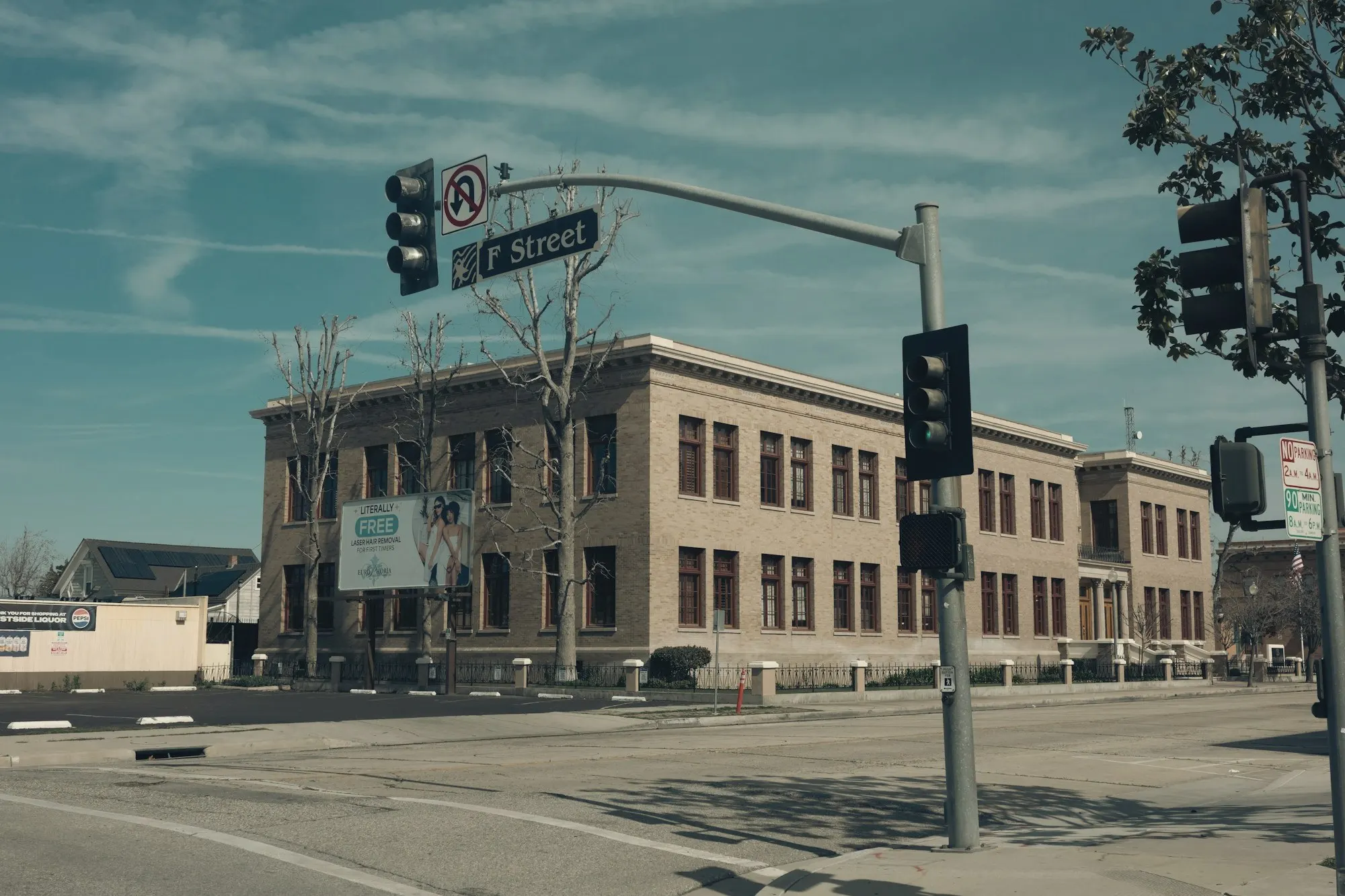 A downtown Bakersfield intersection with traffic lights and a historic brick building.