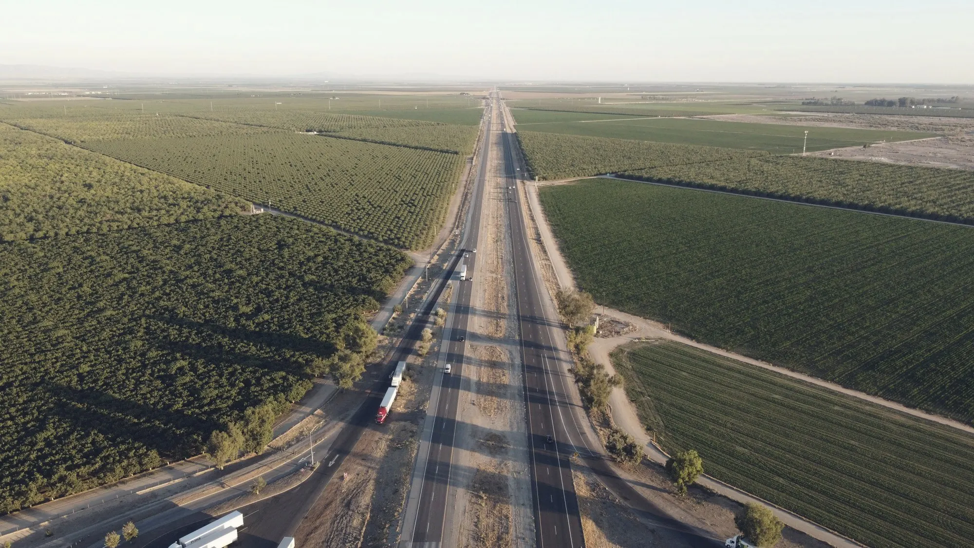 Aerial view of a straight highway running between farm fields in the Central Valley.