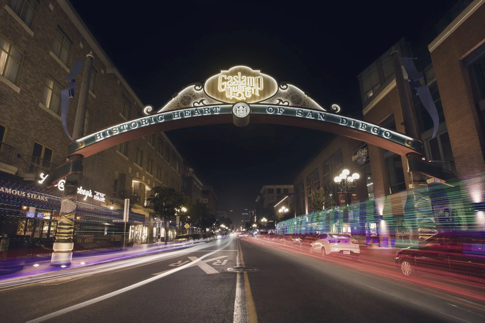 The Gaslamp Quarter archway over a San Diego street with light trails at night.