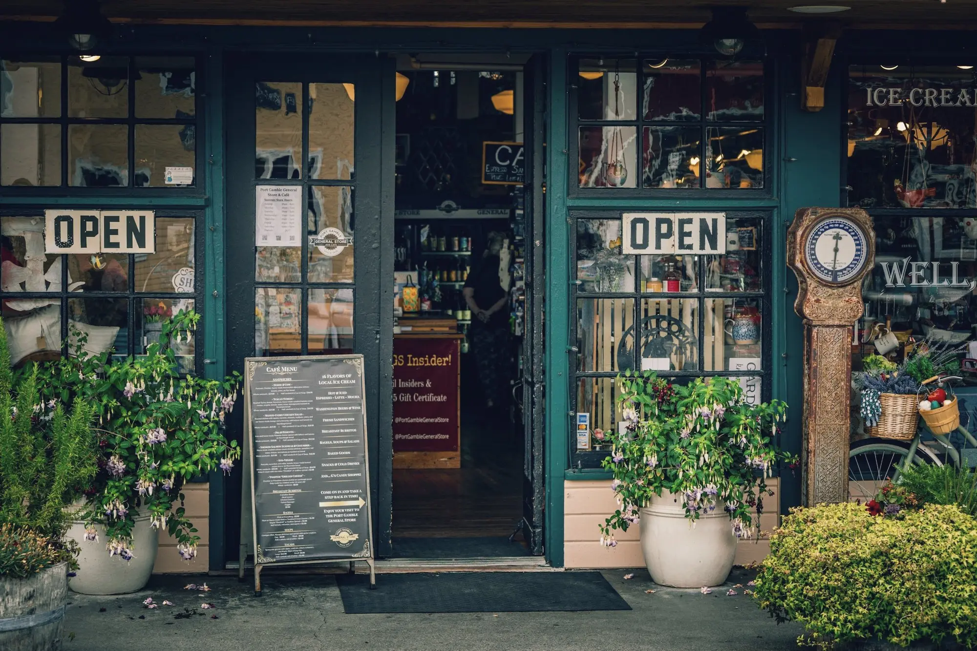 A small shop entrance with open signs, potted plants and a chalkboard.