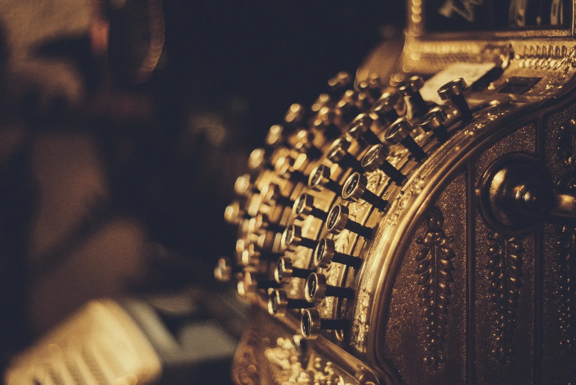 Brass keys of an antique cash register in warm light.