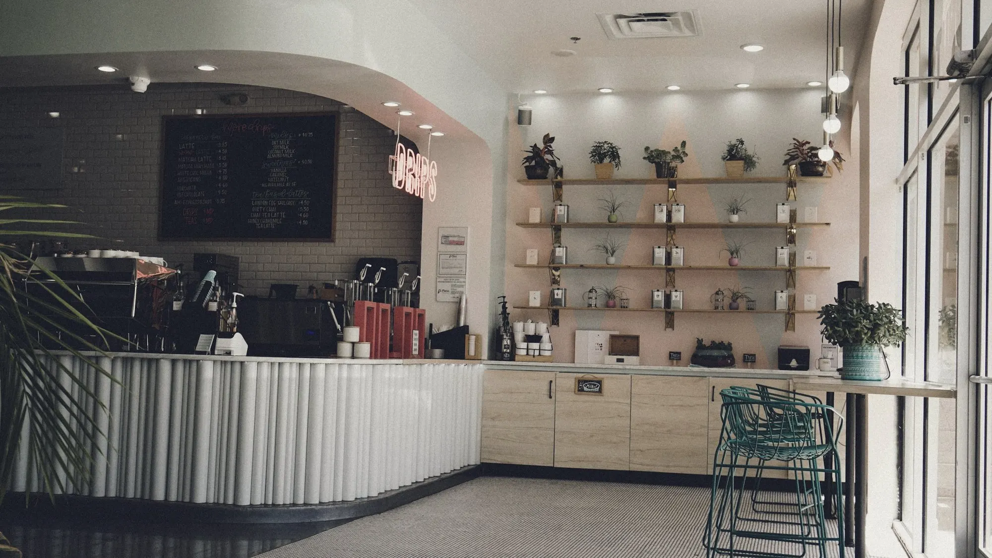A bright café counter with shelves and stools near the entrance.